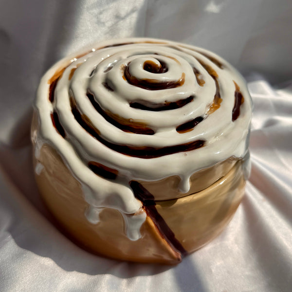 Cinnamon roll with white icing on a white fabric background