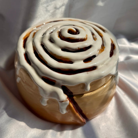 Cinnamon roll with white icing on a white fabric background