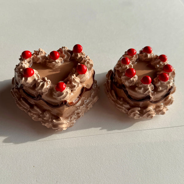 Two small chocolate cakes with red berries on a white surface