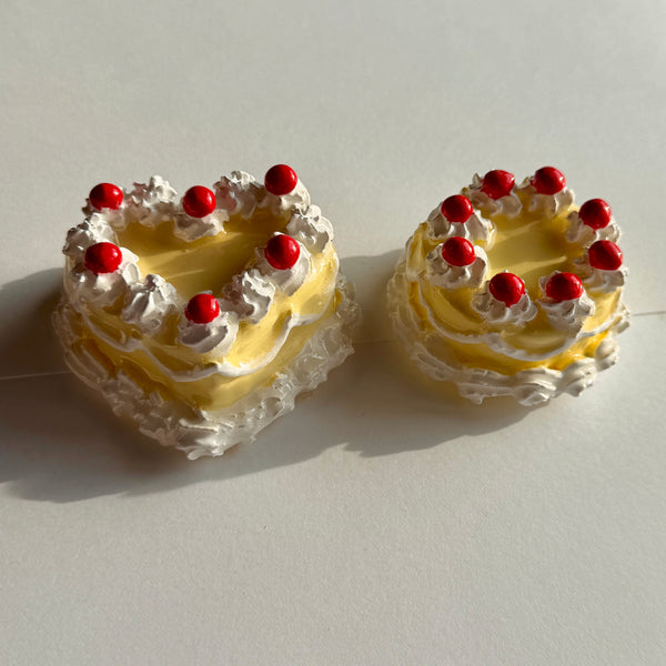 Two cakes with yellow frosting and red berries on a light background